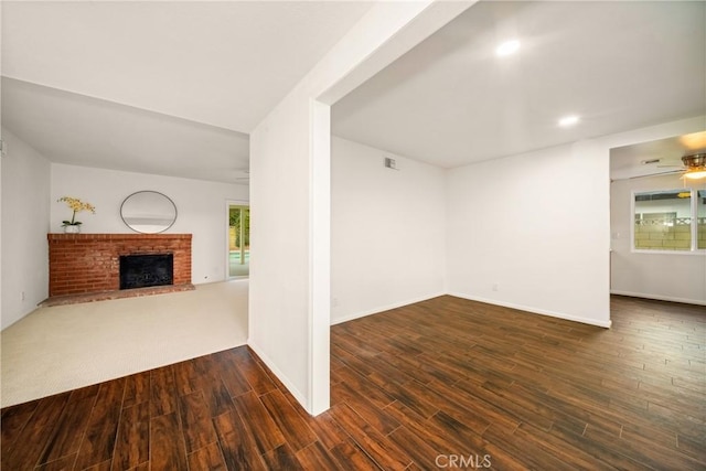 unfurnished living room featuring dark hardwood / wood-style floors, ceiling fan, and a fireplace