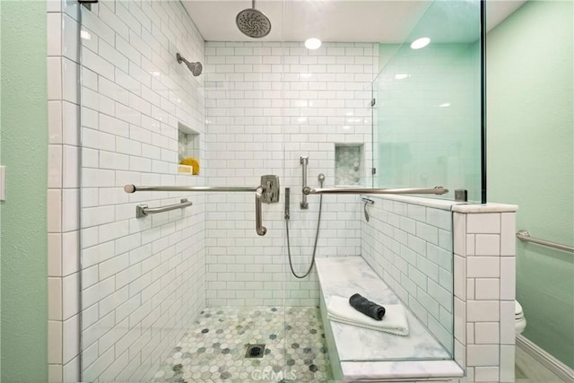 bathroom with a shower with shower door and toilet