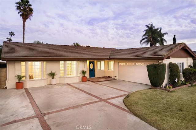 ranch-style home with a garage and a lawn