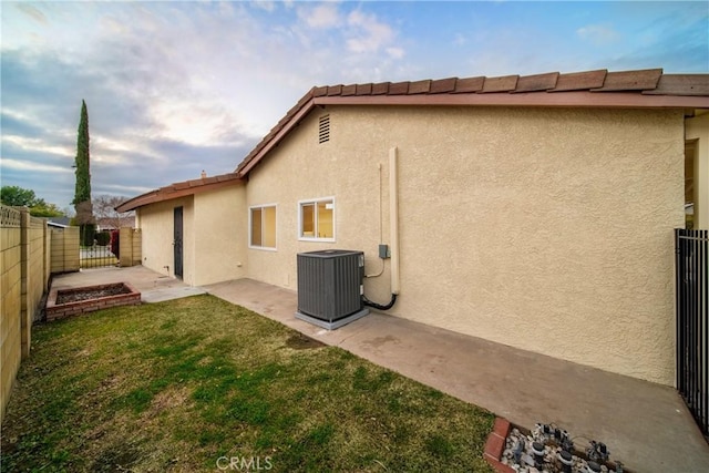 rear view of property with cooling unit, a patio area, and a lawn