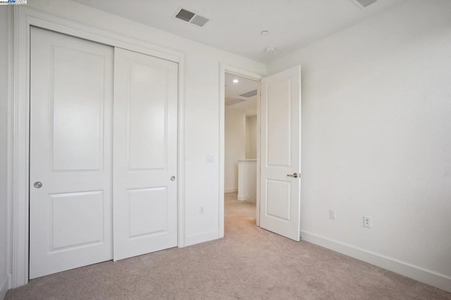 unfurnished bedroom with light carpet and a closet