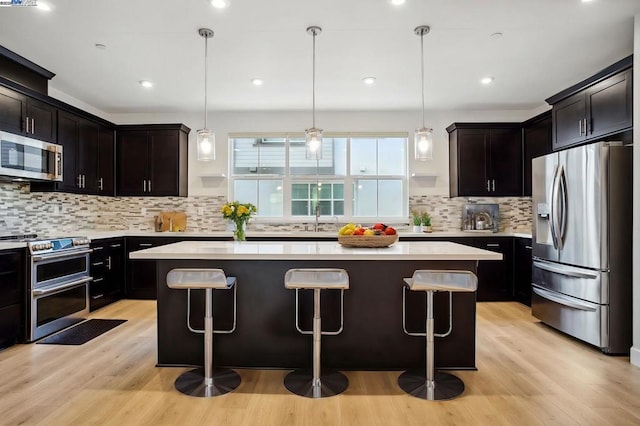 kitchen featuring a kitchen island, appliances with stainless steel finishes, sink, and hanging light fixtures