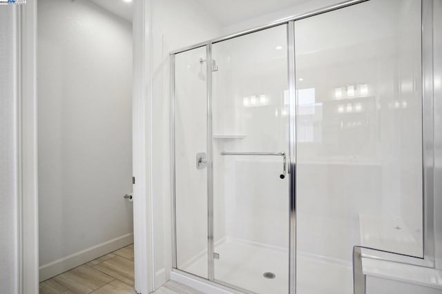 bathroom featuring a shower with shower door and hardwood / wood-style floors