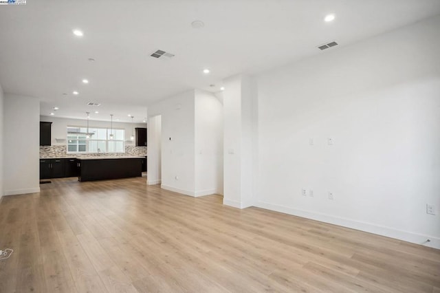 unfurnished living room with sink and light hardwood / wood-style flooring