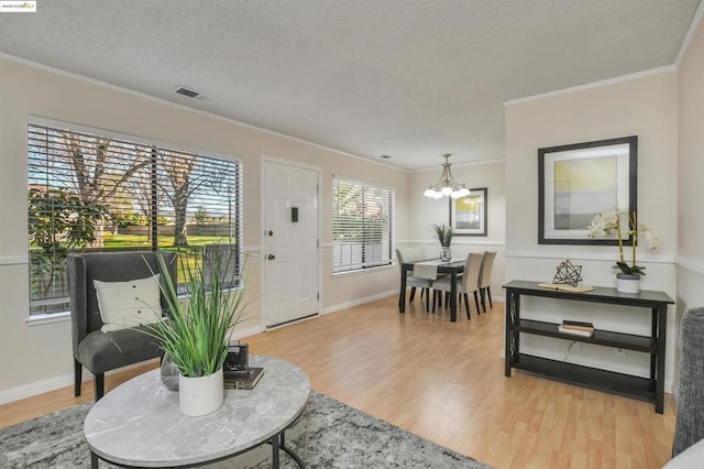 living room featuring crown molding, hardwood / wood-style floors, a textured ceiling, and an inviting chandelier