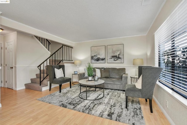 living room featuring ornamental molding, light hardwood / wood-style floors, and a textured ceiling