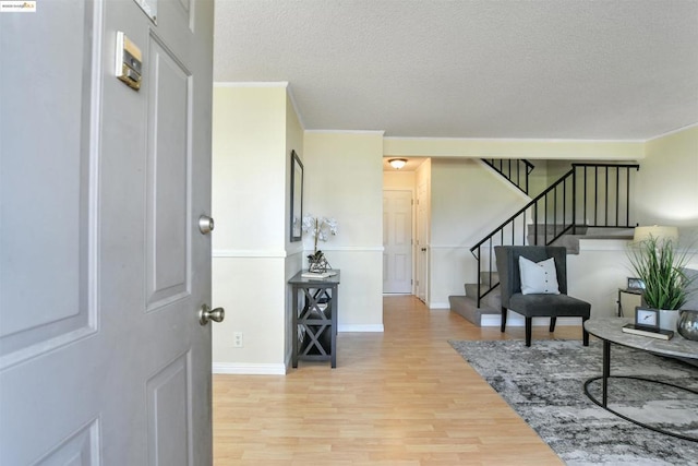 entryway featuring hardwood / wood-style floors, crown molding, and a textured ceiling