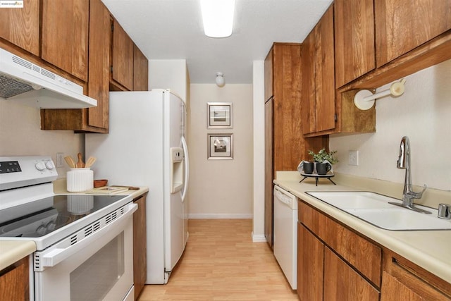 kitchen with sink, white appliances, and light hardwood / wood-style floors