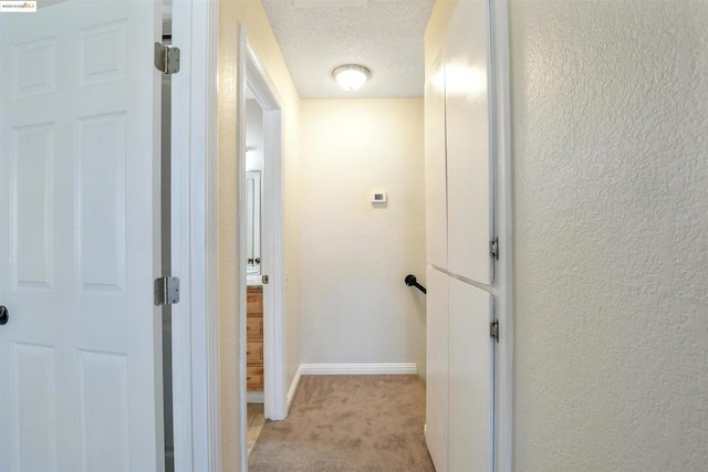 hallway with light colored carpet and a textured ceiling