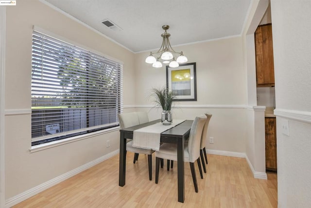 dining area featuring ornamental molding, a chandelier, and light hardwood / wood-style flooring