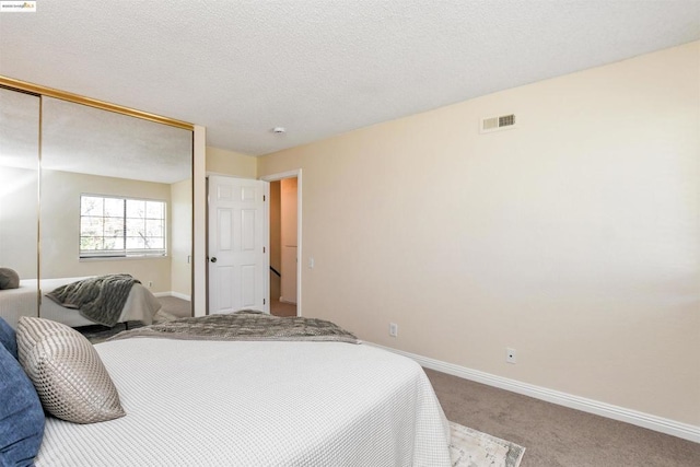 carpeted bedroom featuring a closet and a textured ceiling