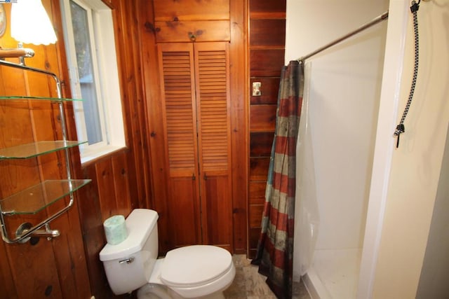 bathroom featuring toilet, wooden walls, and a shower with shower curtain