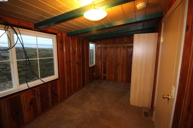 interior space featuring carpet flooring, wooden ceiling, beam ceiling, and wood walls