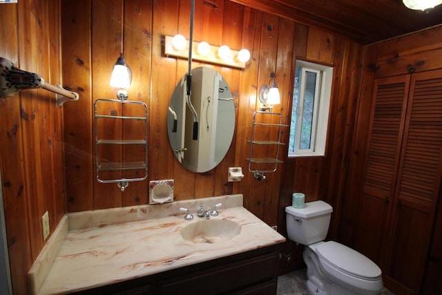 bathroom with vanity, wooden walls, and toilet