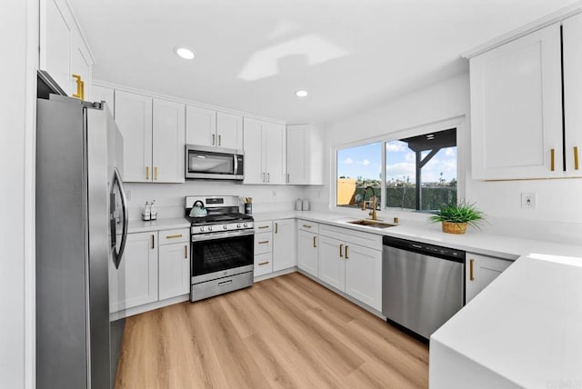 kitchen featuring white cabinetry, appliances with stainless steel finishes, sink, and light hardwood / wood-style flooring