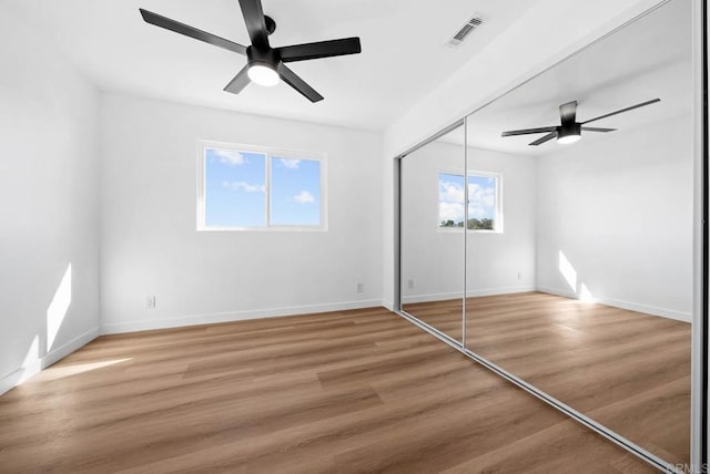 unfurnished bedroom with wood-type flooring, ceiling fan, and a closet