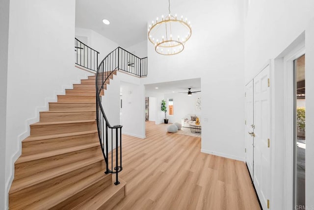 entrance foyer featuring an inviting chandelier, a towering ceiling, plenty of natural light, and light wood-type flooring