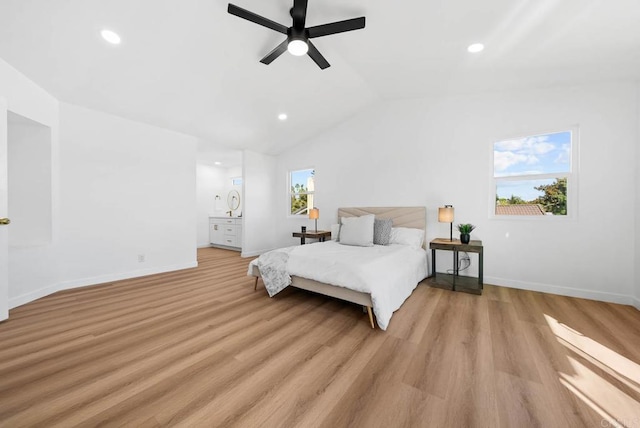 bedroom featuring vaulted ceiling, ceiling fan, light hardwood / wood-style floors, and ensuite bath