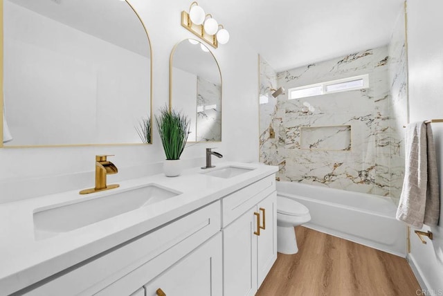 full bathroom featuring wood-type flooring, toilet, tiled shower / bath combo, and vanity