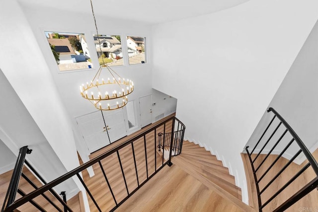 stairway featuring hardwood / wood-style flooring, a chandelier, and a towering ceiling