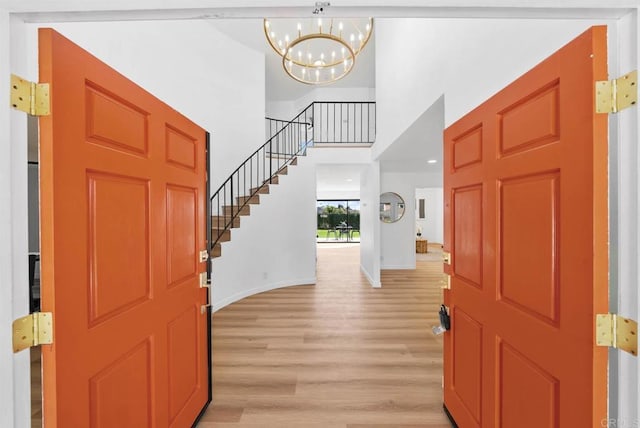 entrance foyer featuring an inviting chandelier, light hardwood / wood-style flooring, and a high ceiling