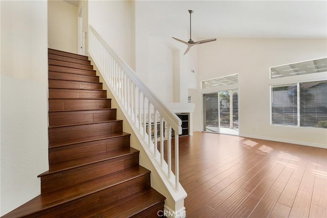 staircase featuring ceiling fan, wood-type flooring, and high vaulted ceiling