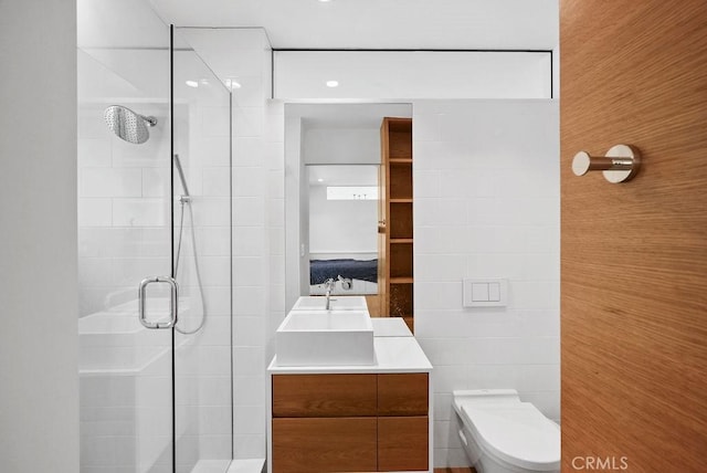 bathroom with vanity, a shower with shower door, tile walls, and toilet