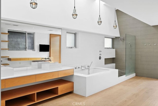 bathroom featuring wood-type flooring, shower with separate bathtub, vanity, and tile walls