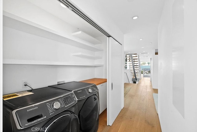 laundry room with washing machine and dryer and light hardwood / wood-style floors