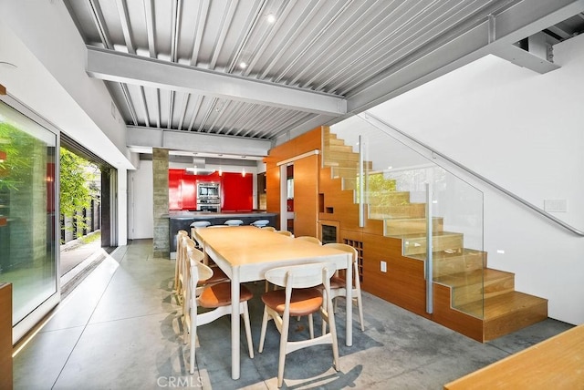 dining room with beam ceiling and concrete floors