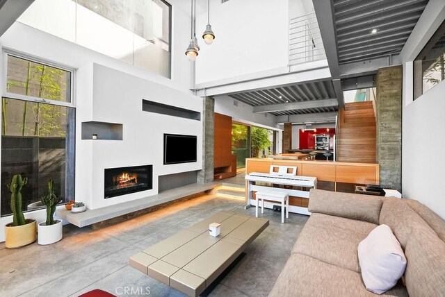 living room featuring a towering ceiling and concrete floors