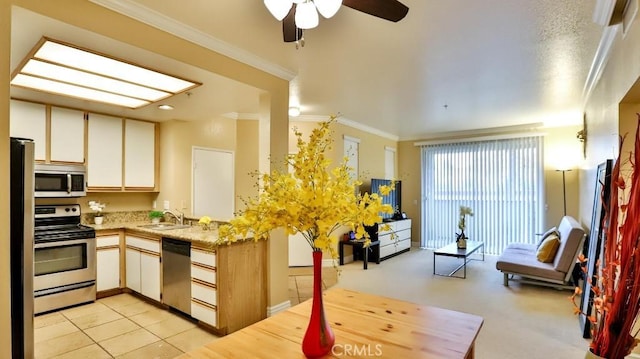 kitchen with ornamental molding, appliances with stainless steel finishes, kitchen peninsula, and sink