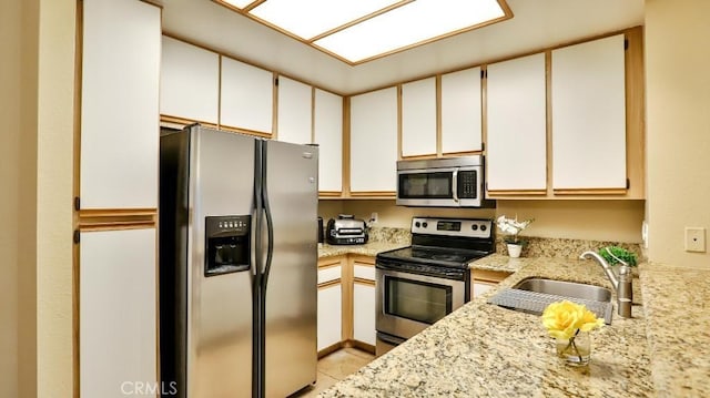 kitchen featuring white cabinetry, sink, light tile patterned floors, and appliances with stainless steel finishes