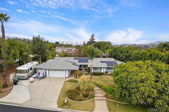 view of front of home with a garage, roof mounted solar panels, and driveway