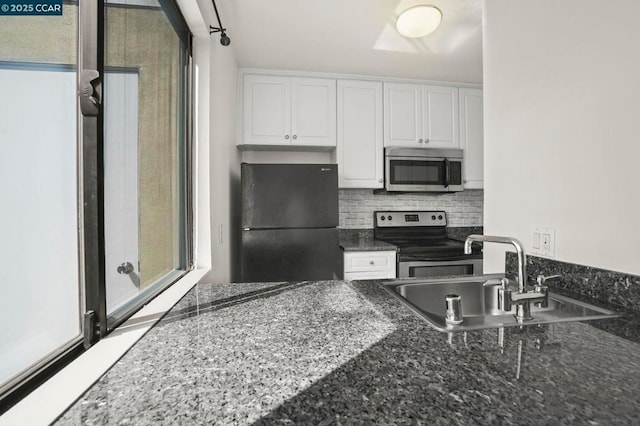 kitchen with sink, white cabinetry, tasteful backsplash, dark stone counters, and stainless steel appliances