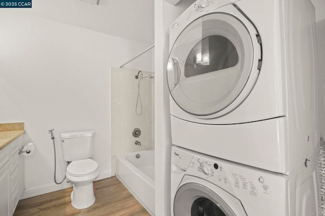 laundry room featuring stacked washer and clothes dryer and light hardwood / wood-style flooring