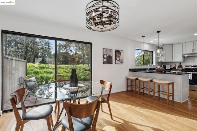 dining space with sink, a chandelier, and light wood-type flooring