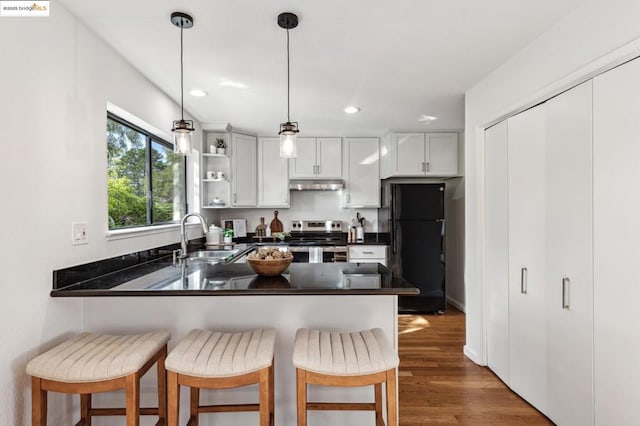 kitchen with black refrigerator, stainless steel range with electric cooktop, kitchen peninsula, and a breakfast bar