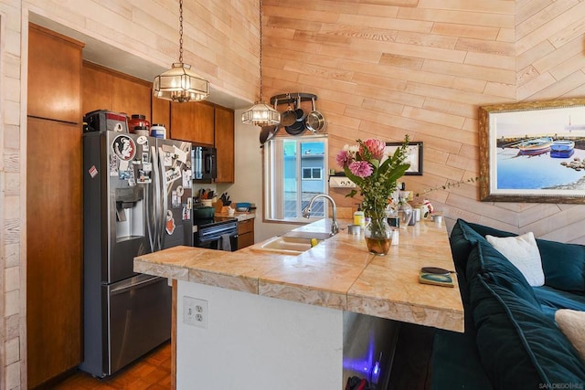 kitchen with black appliances, sink, a breakfast bar area, hanging light fixtures, and kitchen peninsula