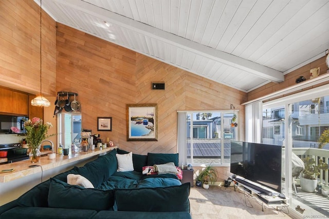 carpeted living room with beamed ceiling and wood walls