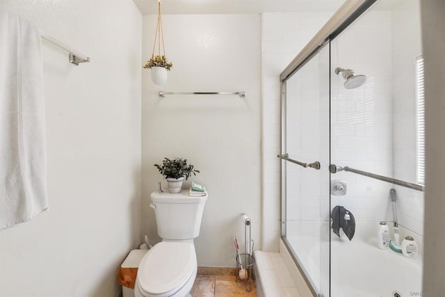 bathroom featuring a shower with door and toilet