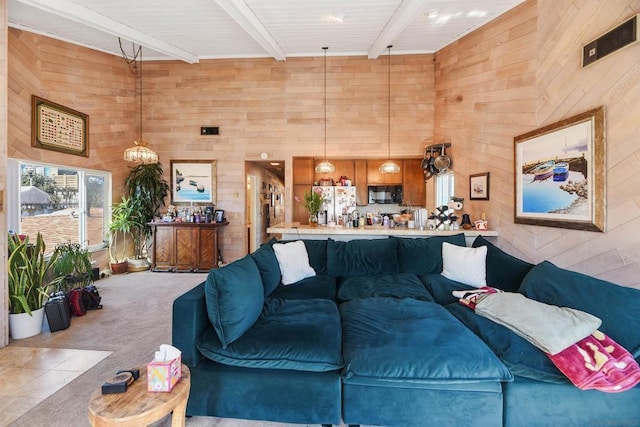 carpeted living room with wooden walls, beamed ceiling, and a high ceiling