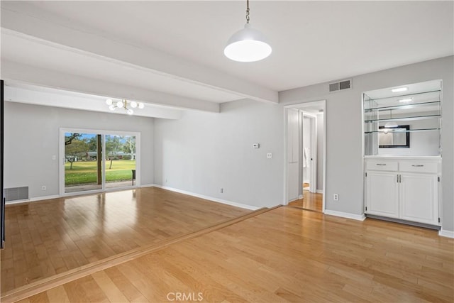 unfurnished living room featuring beam ceiling, a chandelier, and light hardwood / wood-style flooring