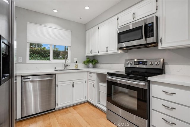 kitchen featuring stainless steel appliances, sink, white cabinets, and light hardwood / wood-style floors