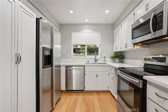 kitchen with stainless steel appliances, light hardwood / wood-style floors, sink, and white cabinets