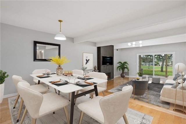 dining space featuring beamed ceiling and light hardwood / wood-style floors