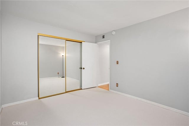 unfurnished bedroom with light carpet and a closet