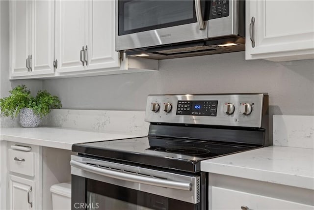 kitchen featuring appliances with stainless steel finishes, white cabinets, and light stone counters