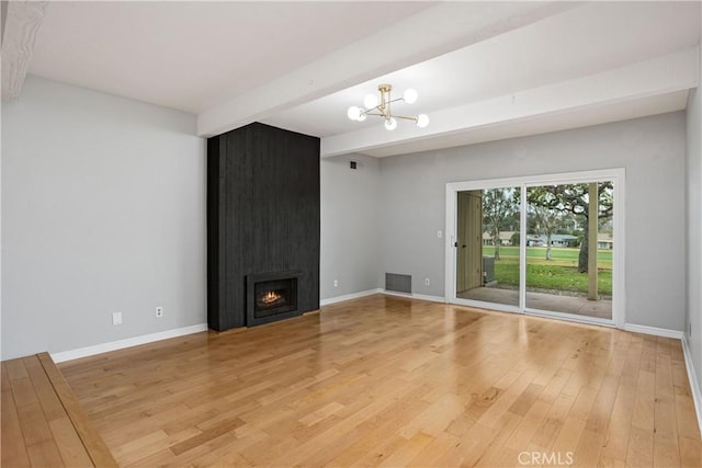 unfurnished living room with hardwood / wood-style floors, beam ceiling, a fireplace, and a notable chandelier