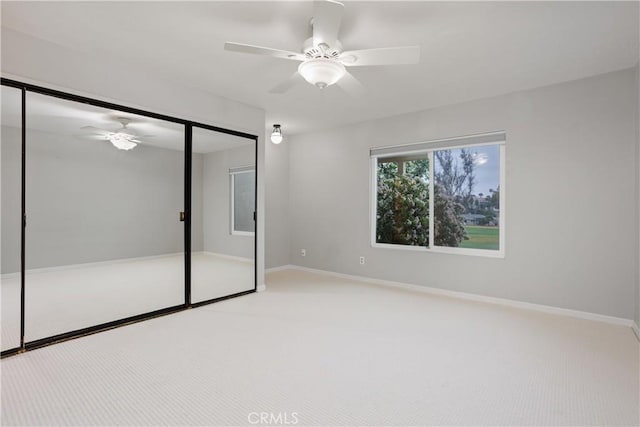 unfurnished bedroom featuring light colored carpet, a closet, and ceiling fan